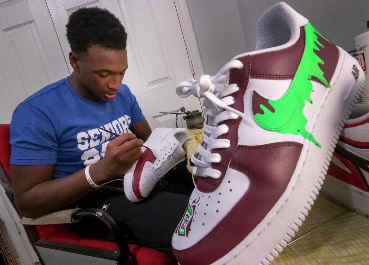 Dickinson High School senior Donovan Green, a star on the school football team, paints custom designs on a sneaker in his bedroom on Jan. 20, 2022.