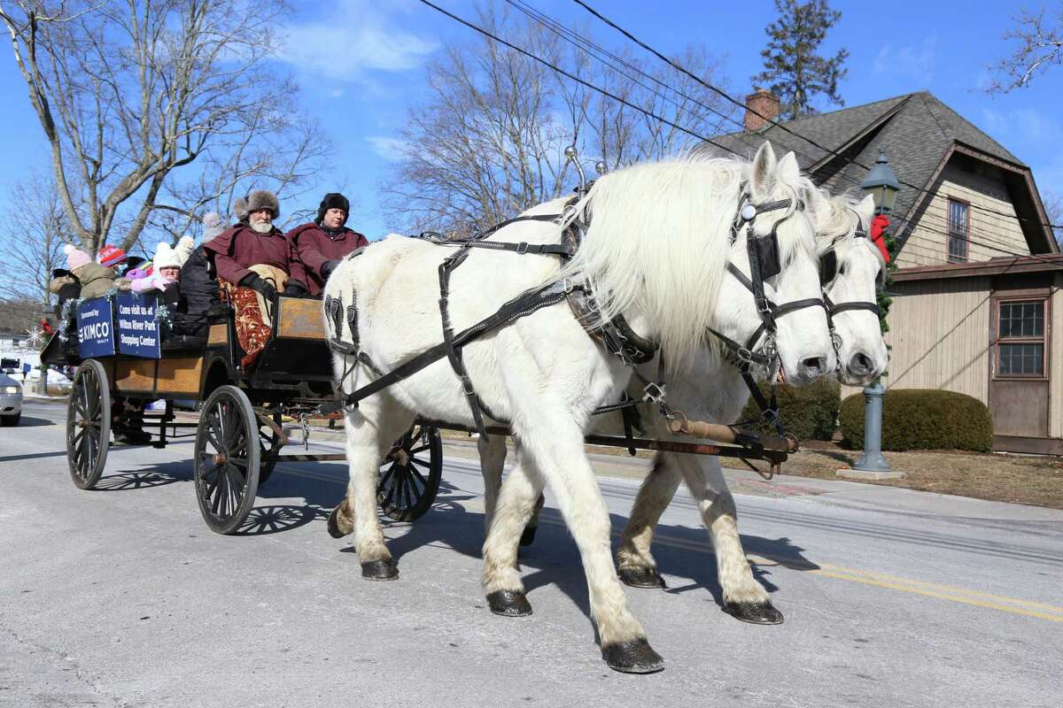 A horse-drawn wagon carries some carnival folk along River Road.