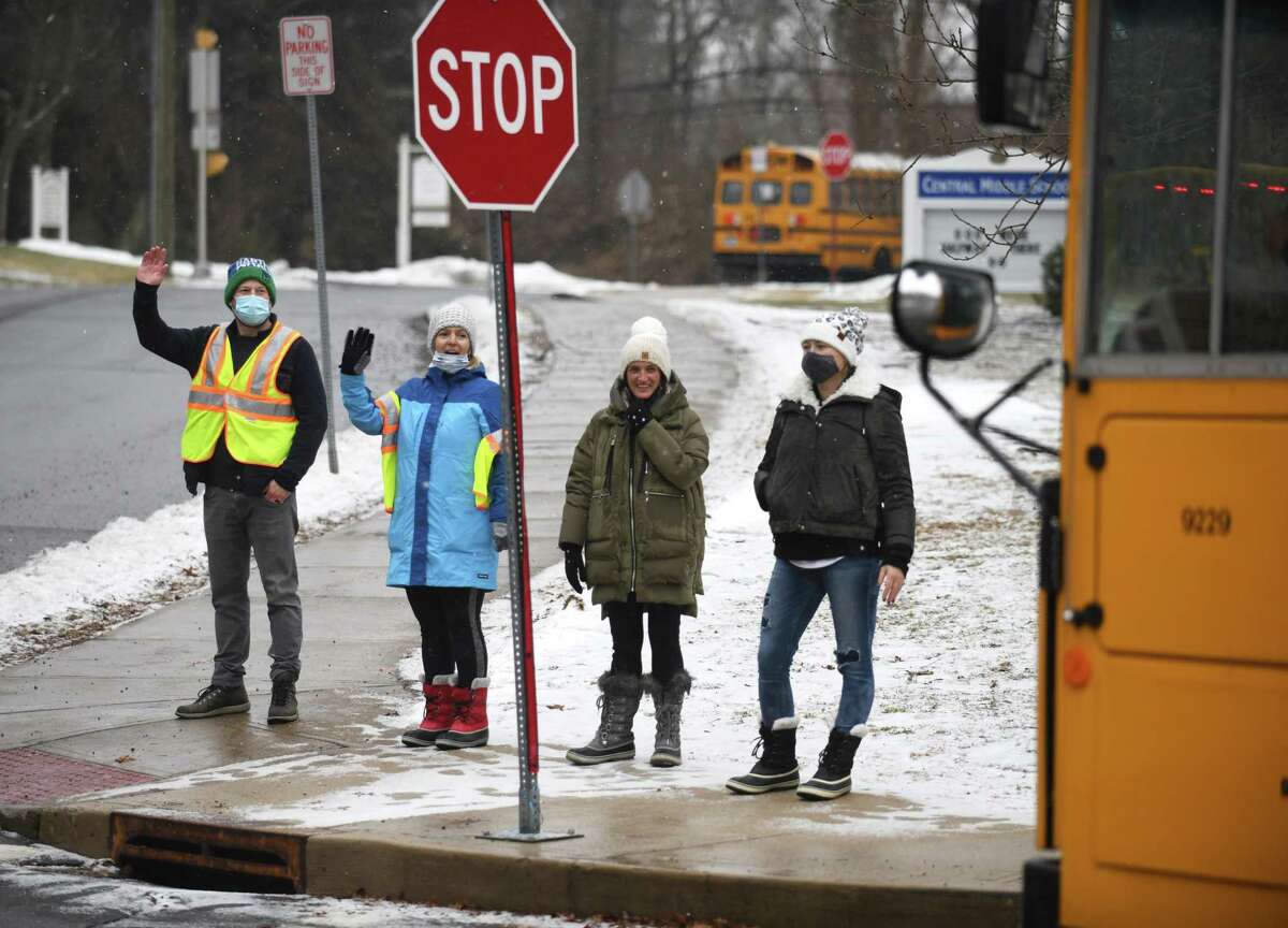 From left, PTA members Brian Zeller, Anne Rockel, Dina Urso, and Gabbi Feinstein wave as shuttle buses take students to different schools from Central Middle School in Greenwich, Conn. Monday, Feb. 7, 2022. Due to safety issues, Central Middle School is closed this week. For the time being, CMS sixth-graders will attend school at Cos Cob School, seventh-graders at Eastern Middle School, and eighth-graders at Greenwich High School.
