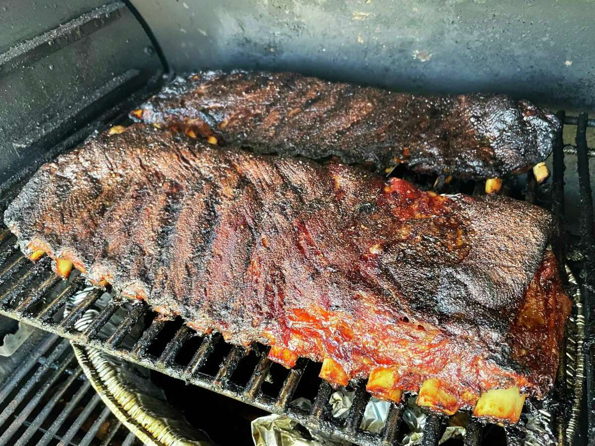 Pork spare ribs are on the smoker with the full slab (front) and St. Louis style in the back.