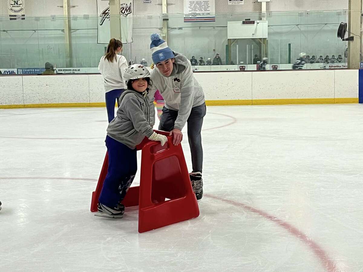 Stephanie Argueta, 7, pushes her way across the ice with an assist from teen mentor Sam Bisesi at the first session of Ice Skating for Everyone at the SoNo Ice House on Feb. 5, 2022.
