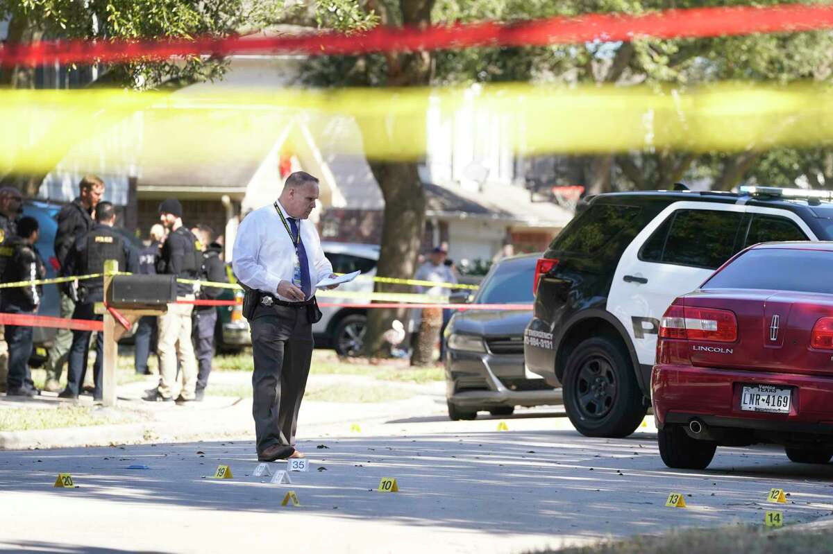Evidence markers are shown on the street as police officers work at the scene in the 800 block of Oak West where Houston police officers shot and killed a robbery suspect who they say opened fire on them during an arrest attempt Monday, Feb. 7, 2022 in Houston.