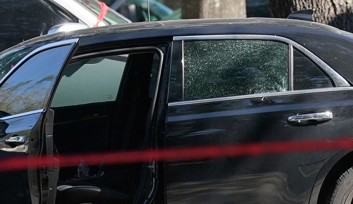 A car with a bullet hole in the back door and shattered glass is shown at the scene in the 800 block of Oak West where Houston police officers shot and killed a robbery suspect who they say opened fire on them during an arrest attempt Monday, Feb. 7, 2022 in Houston.