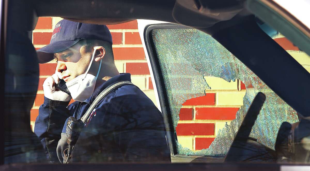 John Badman|The Telegraph An Alton Fire Department paramedic talks on his phone near the side window of a pickup truck which was broken during the arrest.