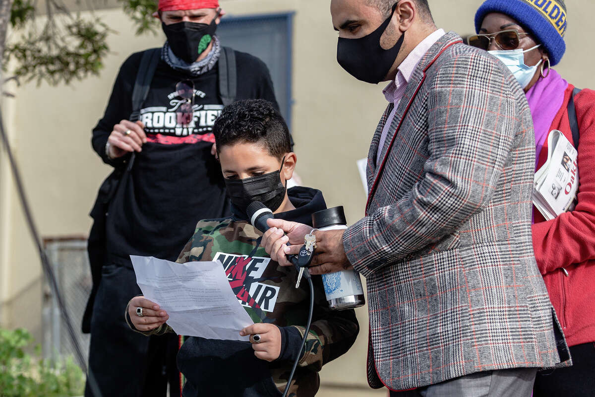 Amir Mohamed, 8, a student at Brookfield Elementary reads aloud his own written words against school closures as his father Mokhtar helps with the microphone, at the Oakland School Solidarity Rally and 4Peace Community Walk, on Saturday morning, Feb. 5, 2022. 