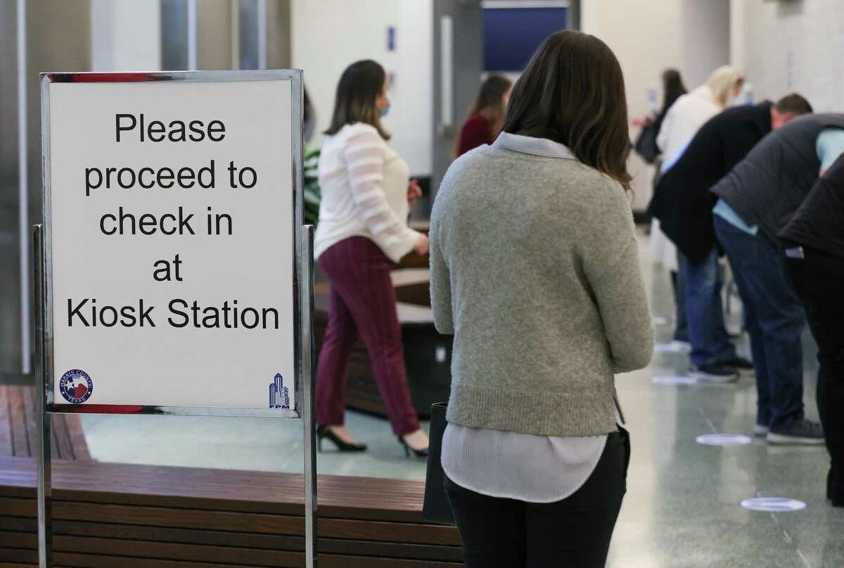Potential jurors check in at a kiosk station before heading to jury assembly rooms at the Harris County Jury Assembly building on Monday, Feb. 7, 2022, in Houston.