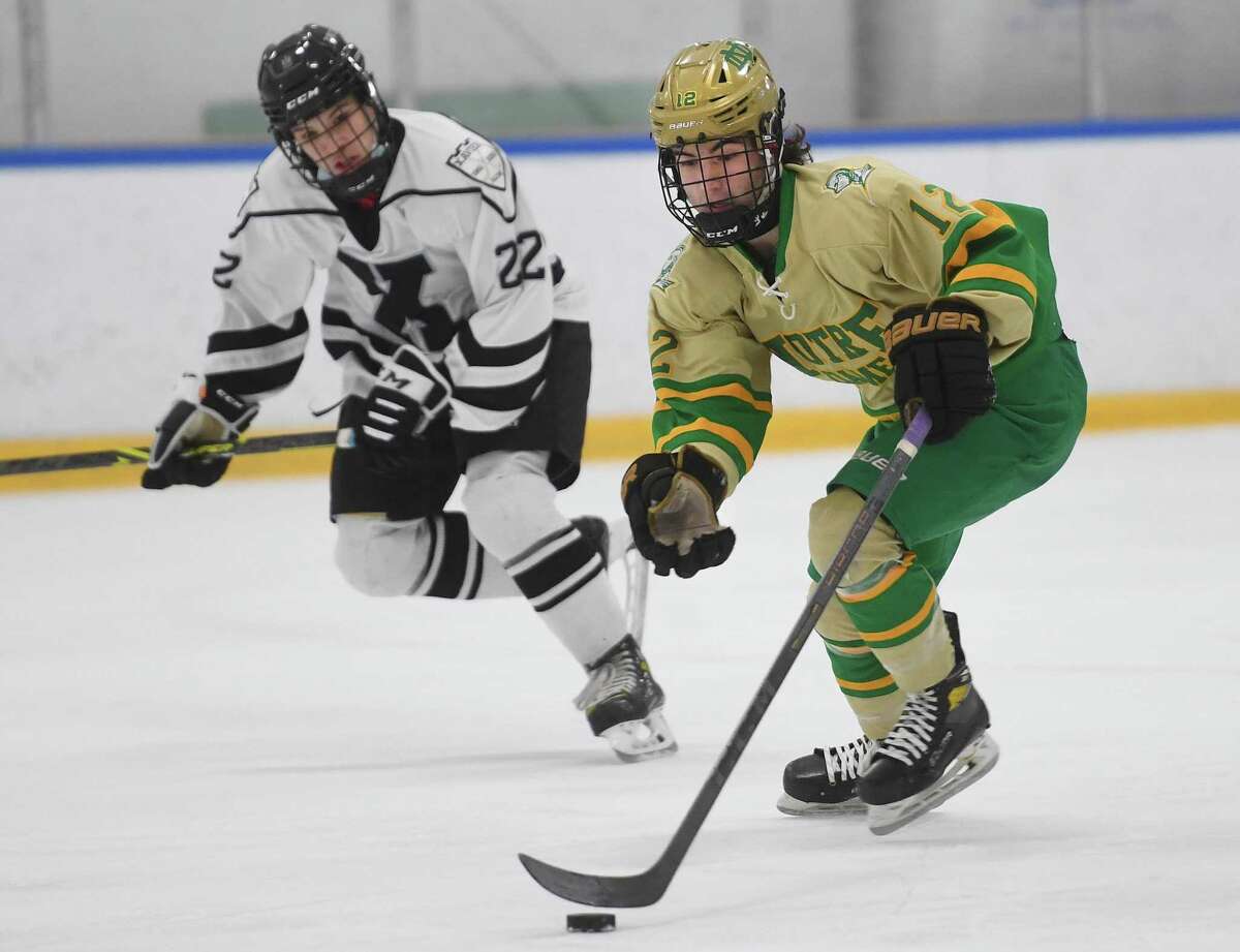 Notre Dame-West Haven’s Mike Troiano races the puck up ice pursued by Xavier’s Michael Prestash at the Champions Skating Center in Cromwell on Tuesday.