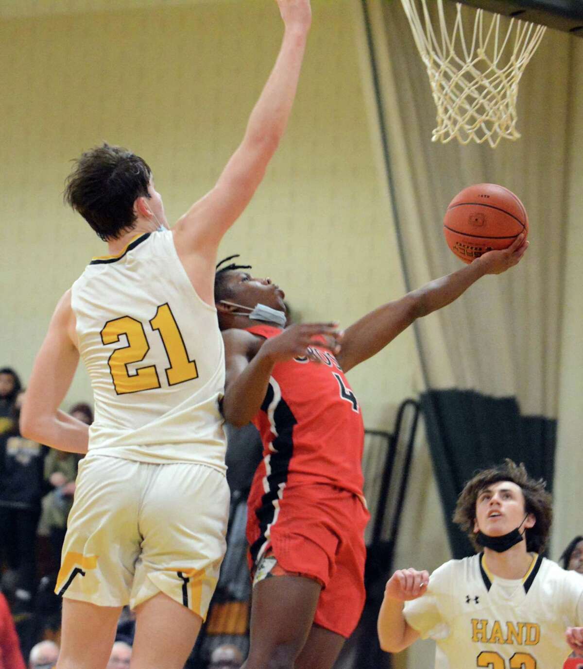 Christian McClease of Wilbur Cross scoops a shot off the glass while being guarded by Tyler Favre of Hand during the Tigers’ 78-50 win on Tuesday in Madison.