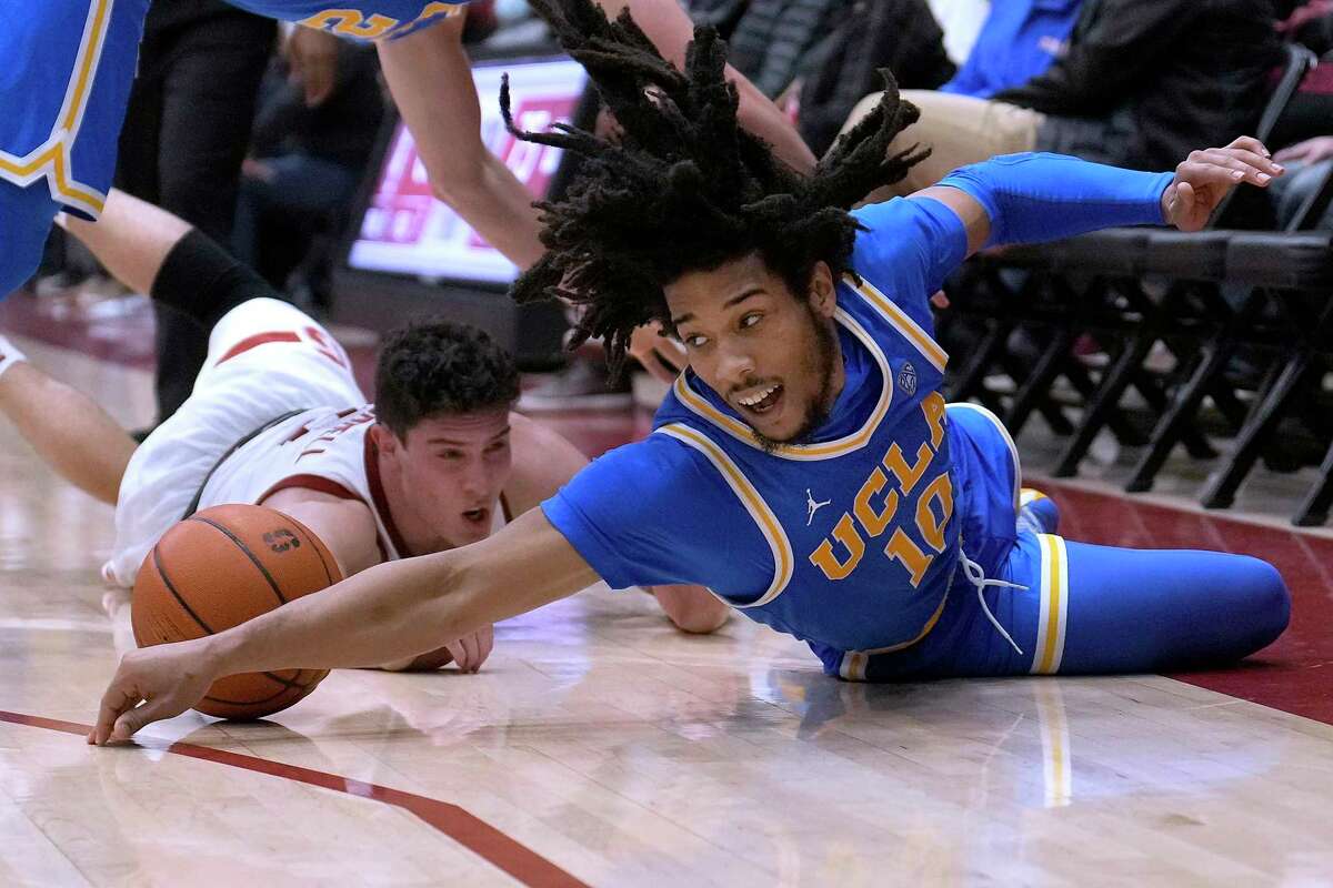 UCLA guard Tyger Campbell (10) dives for the ball in front of Stanford guard Michael O'Connell, left, during the second half of an NCAA college basketball game in Stanford, Calif., Tuesday, Feb. 8, 2022. UCLA won 79-70. (AP Photo/Tony Avelar)