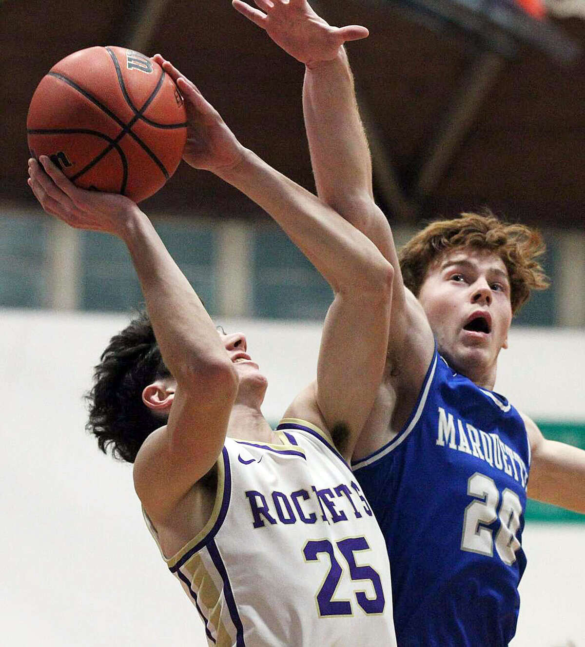 Brody Hendricks of Marquette (20) defends as Jacksonville Routt's Ethan Walker goes up for a shot Tuesday night in Jacksonville.