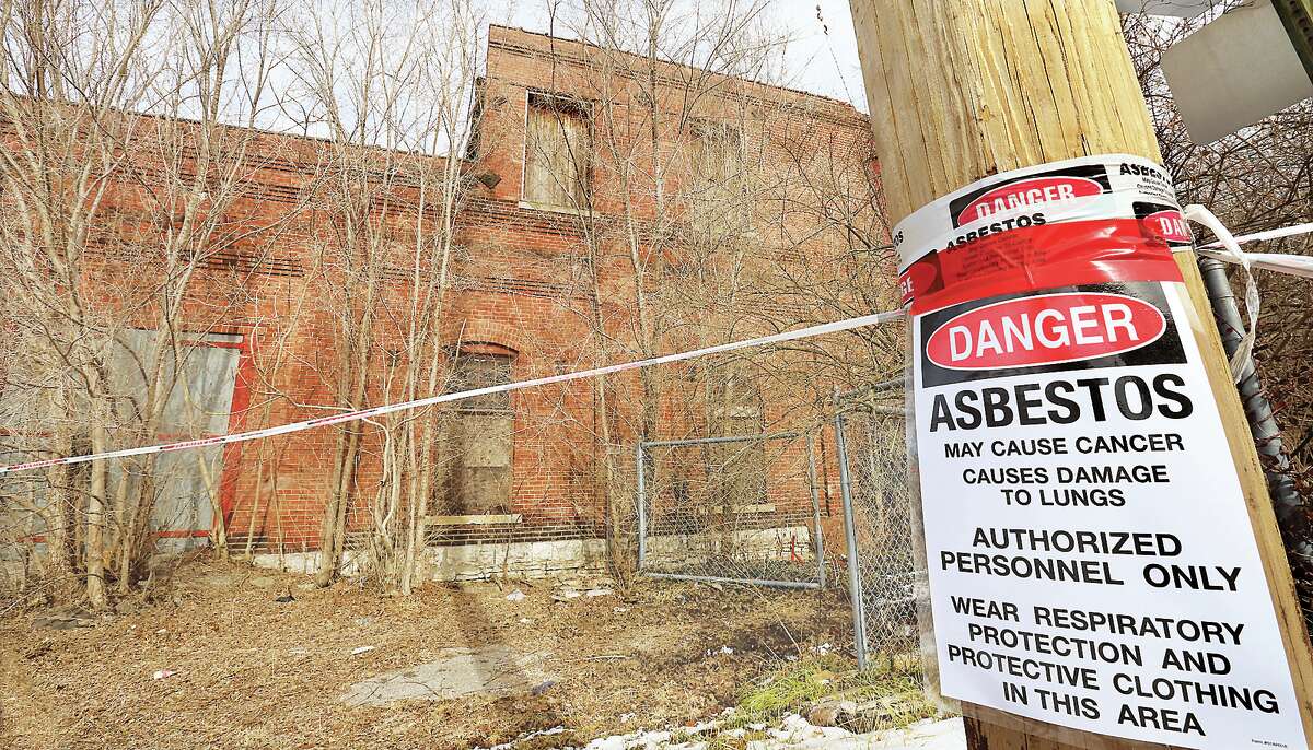 John Badman|The Telegraph A sign Wednesday on the south end of the nearly 130-year-old building in Alton which once housed artist Arthur Towata's workshop warns of an asbestos hazard. The building is being razed.