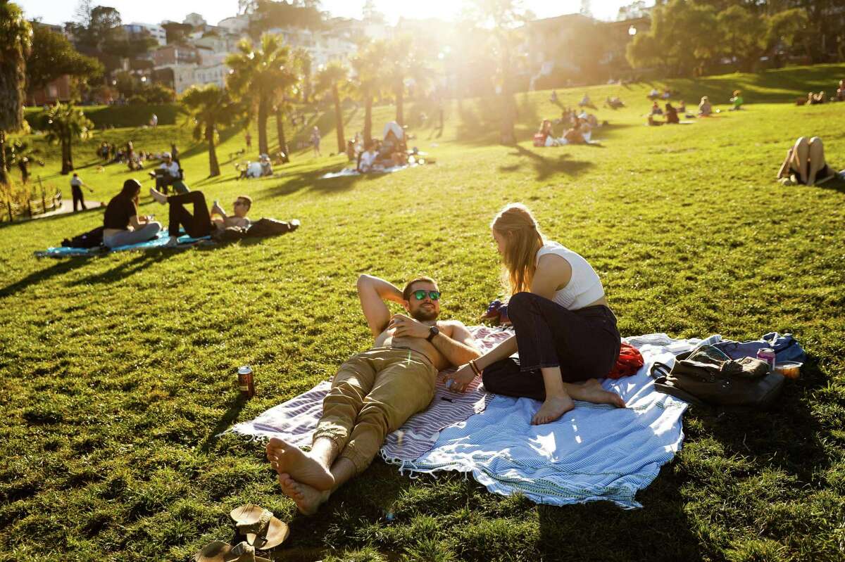 Jackson Rich and Katharine Greenthal relax on the grass at Dolores Park on a warm day in San Francisco, Calif. The Bay Area was bracing for a “weather roller coaster” in the coming days, expected to bring wild swings in temperatures.