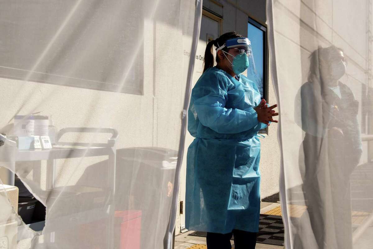 Medical assistant Bianca Zarco, left, and medical assistant supervisor Judith Placencia are seen through a waiting area tent door while they prepare to administer COVID-19 tests to patients outside Petaluma Health Center in Petaluma, Calif., on Monday, Jan. 24, 2022.