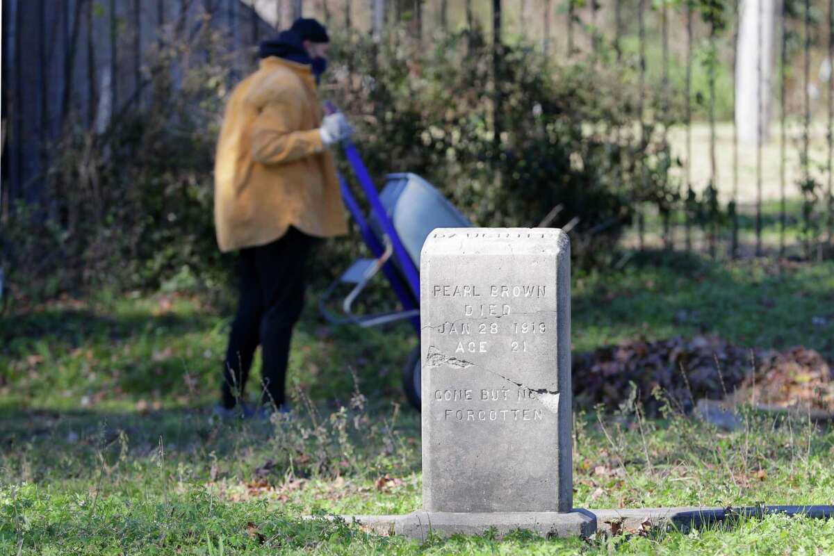 Volunteer Frances-Amanda Stallworth dumps a wheel barrel full of leaves along the west fence line as she and other volunteers clean up the area around grave plots at the historically black Olivewood cemetery Saturday, Feb. 5, 2022 in Houston, TX.