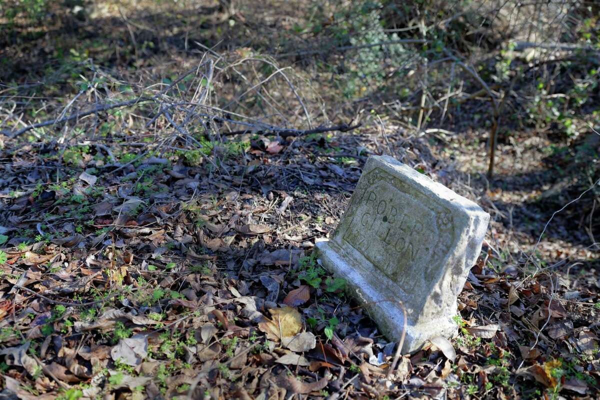 The headstone and plot of Robert Gillon is nearly washed away by the expanding creek on the north end of the historically black Olivewood cemetery Saturday, Feb. 5, 2022 in Houston, TX. Volunteers were on hand to assist with cleaning up the cemetery.