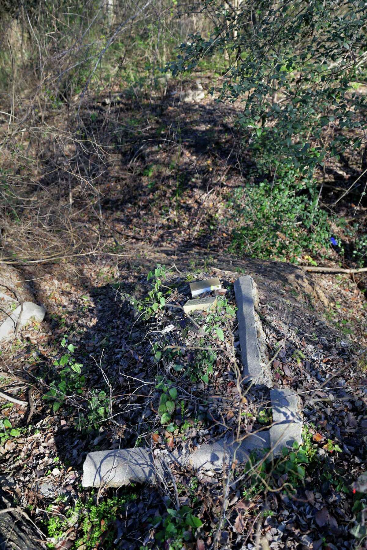 Graves plots are being washed up by rain water runoff into the creek at the north end of the historically black Olivewood cemetery Saturday, Feb. 5, 2022 in Houston, TX. Some five volunteers spent the morning weed whacking, raking leaves and doing general clean up across the cemetery.