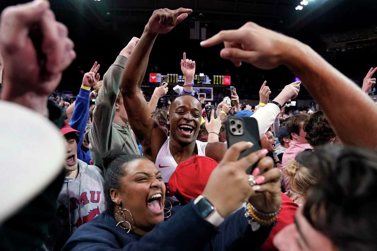 SMU's Zach Nutall, center, celebrates with fans who rushed the court after SMU's 85-83 win against Houston in an NCAA college basketball game in Dallas, Wednesday, Feb. 9, 2022. (AP Photo/Tony Gutierrez)
