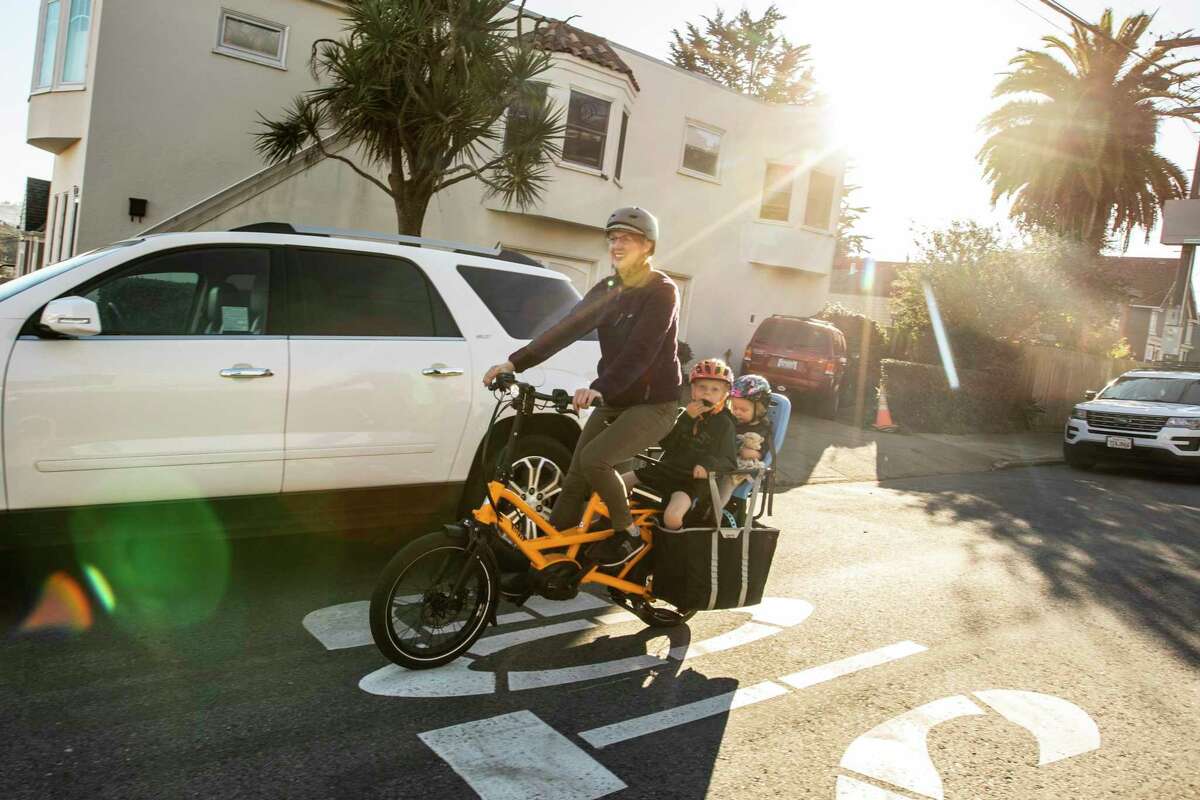 罗宾·帕姆带着儿子帕克斯和女儿维拉骑着电动自行车在旧金山赫斯特大道上进行足球训练。当大流行期间交通选择减少时，帕姆开始骑电动自行车。她并不打算放弃自行车而只依靠交通工具。