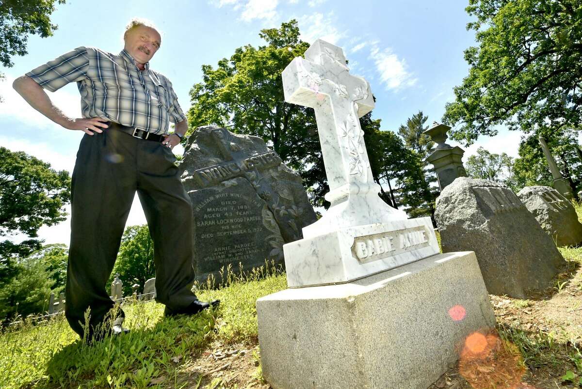 Dale J. Fiore, general manager of the Evergreen Cemetery Association and Crematory in New Haven, next to the newly restored grave marker for “Baby Annie” Winchester, granddaughter of the founder of Winchester Repeating Arms Co., Oliver Winchester.