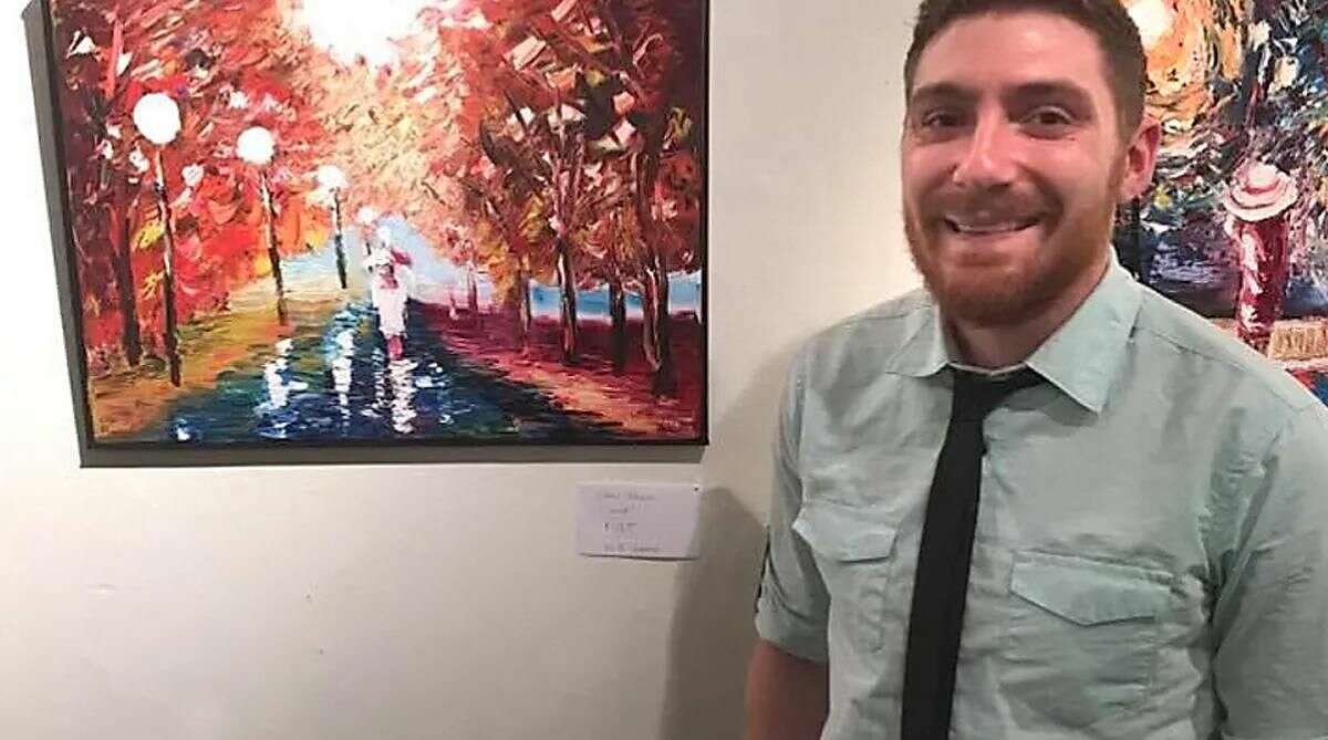 Chris Brown with one of his paintings, now on display at Noah Webster Library.