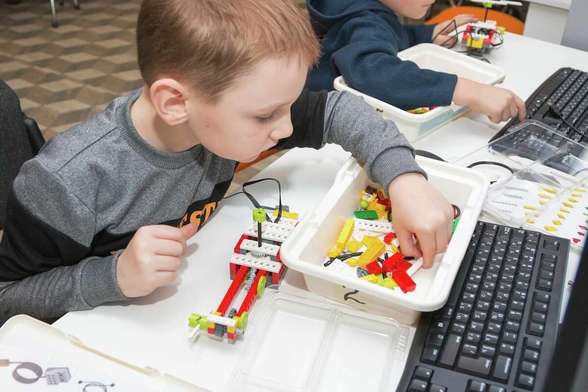 A boy picks out a LEGO piece to incorporate into his STEAM creation.