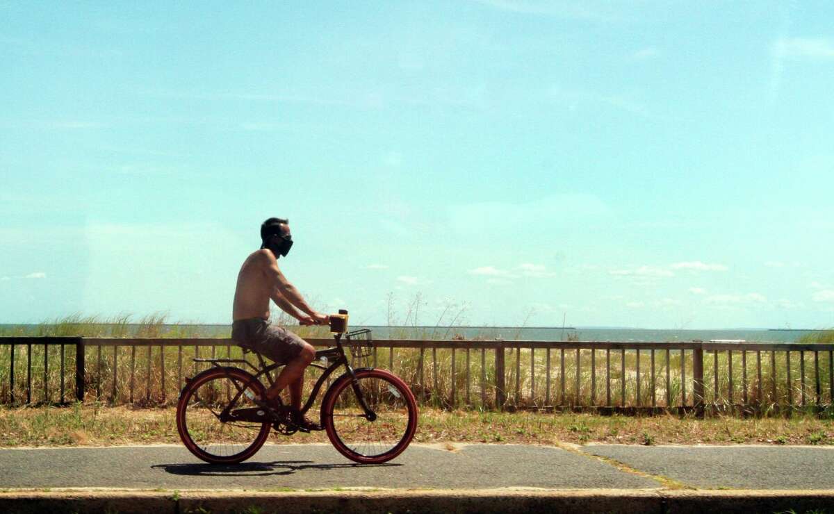 A file photo of a man riding a bike along Beach Street in West Haven, Conn. The current forecasts are showing temperatures near 90 degrees in Connecticut this weekend, May 22 and May 23, 2021.