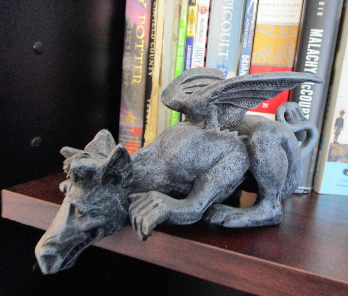 From its bookshelf perch, a gargoyle keeps watch.