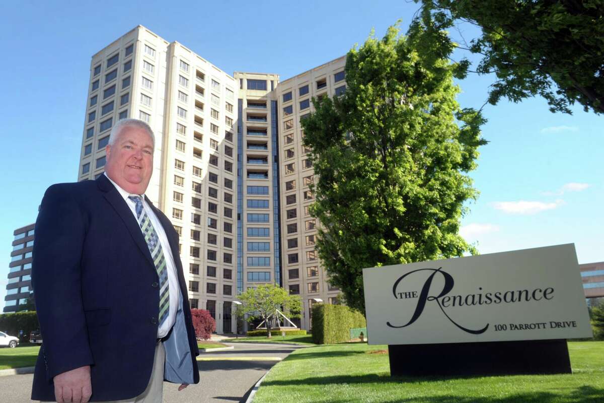 State Rep. Ben McGorty, a real estate agent for Coldwell Bankers Realty, stands in front of The Renaissance tower in Shelton, Conn. May 12, 2021.