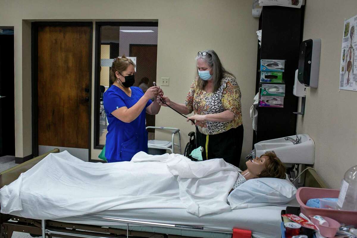 Sofia Morales takes a stethascope from instructor Wendy Coleman before practicing taking a patient’s blood pressure during her CNA training class at Restore Education in San Antonio, Texas, on Feb. 9, 2022. Restore Education is one of the primary providers of training courses for participants in the city's Train for Jobs and soon, Ready to Work, programs.
