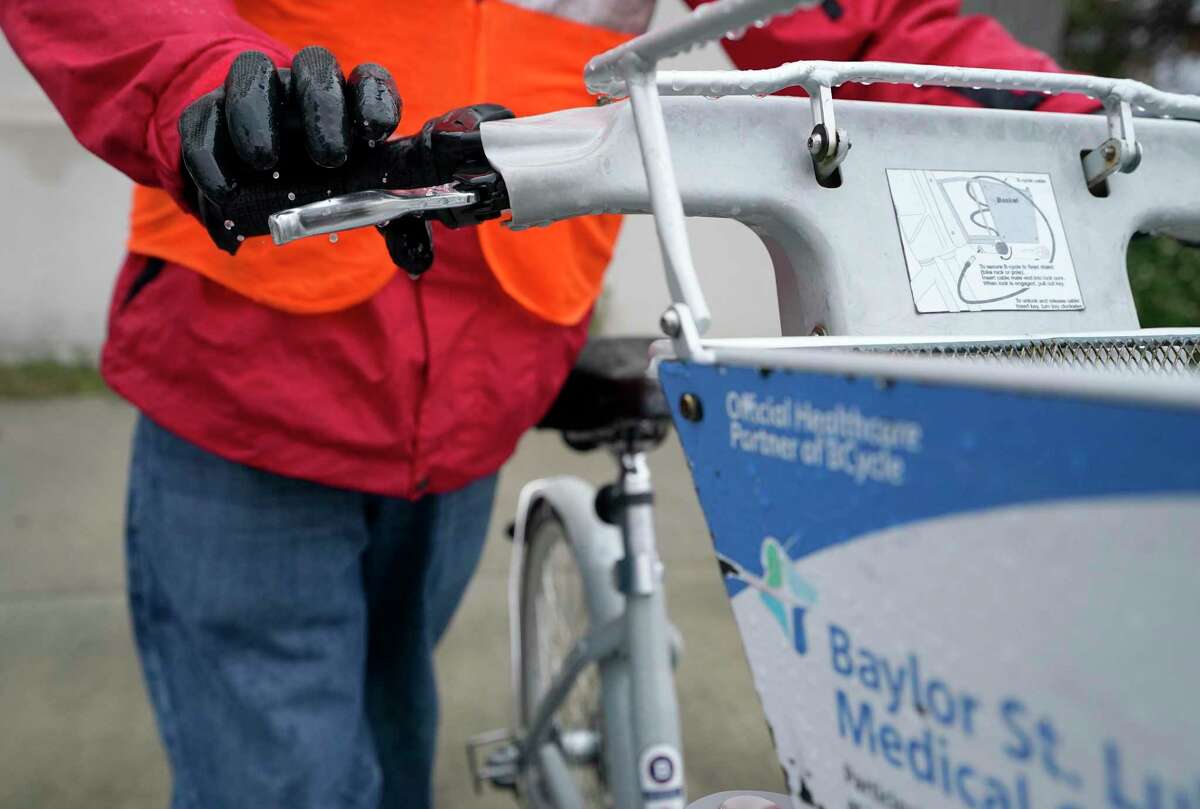 Ian Freeman, e-trike operator, check the brake as he collects bikes at the 8th Wonder BCycle station Thursday, Feb. 3, 2022 in Houston.