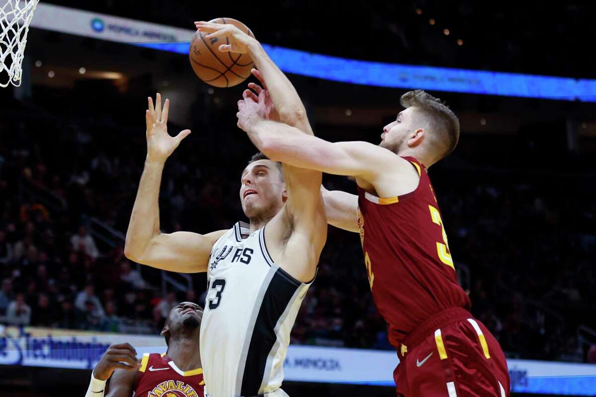 San Antonio Spurs' Zach Collins (23) battles Cleveland Cavaliers' Dean Wade (32) for a rebound during the second half of an NBA basketball game, Wednesday, Feb. 9, 2022, in Cleveland. The Cavaliers defeated the Spurs 105-92. (AP Photo/Ron Schwane)