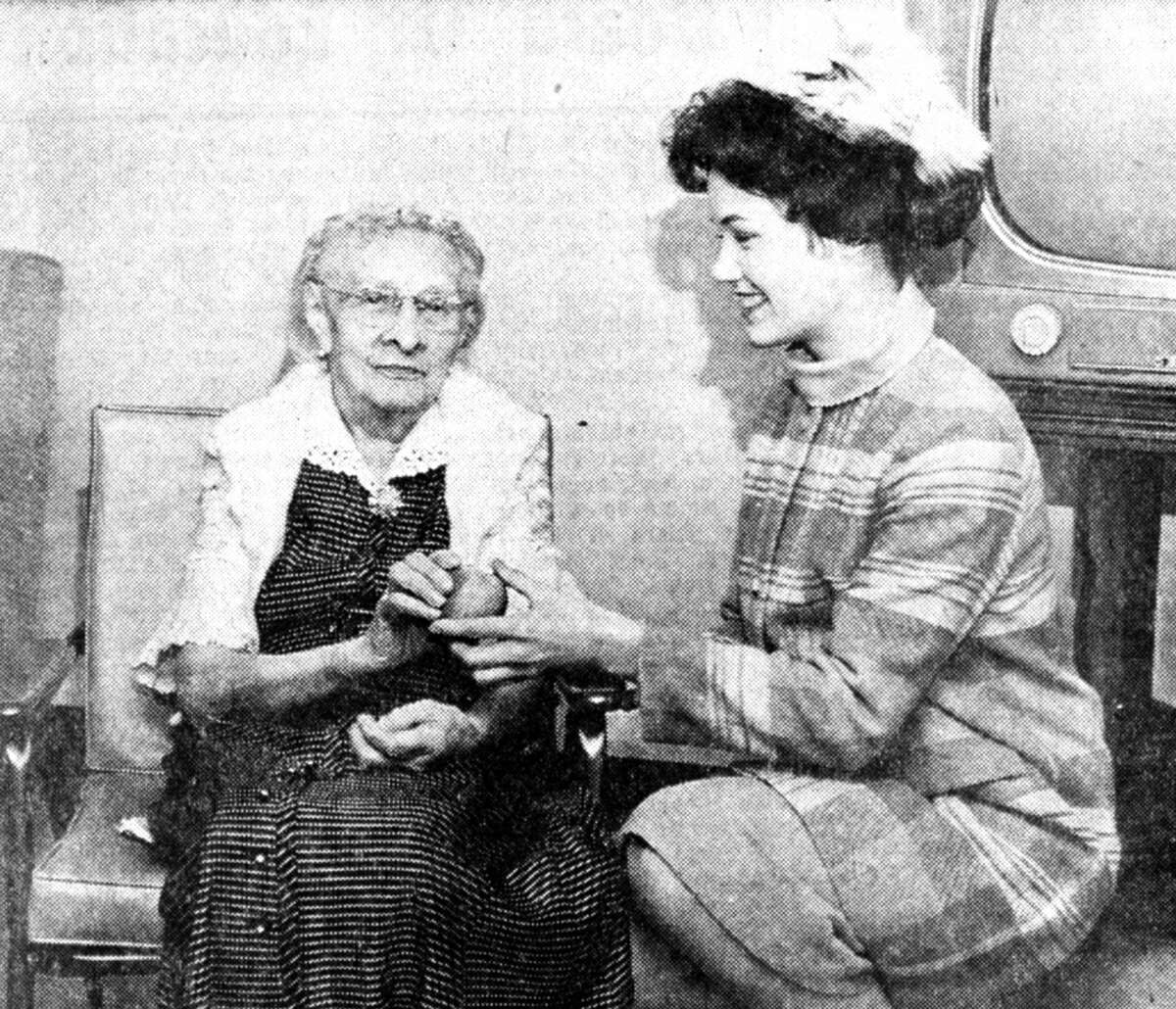 Although the Saturday morning arrival of Nancy Fleming, Miss America 1961 was delayed somewhat, she was able to fill the schedule of activities arranged by the sponsoring board of commerce. The first was to the Manistee County Medical Care Facility where she greeted a number of the patients. Fleming could be seen here giving an apple and smile to Mary Bosschem. The photo was published in the News Advocate on Feb. 12, 1962.