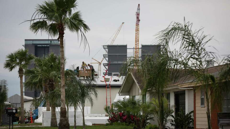 Men install solar panels on the roof of a building as construction continues at a SpaceX facility Thursday, Feb. 10, 2022, in Boca Chica.
