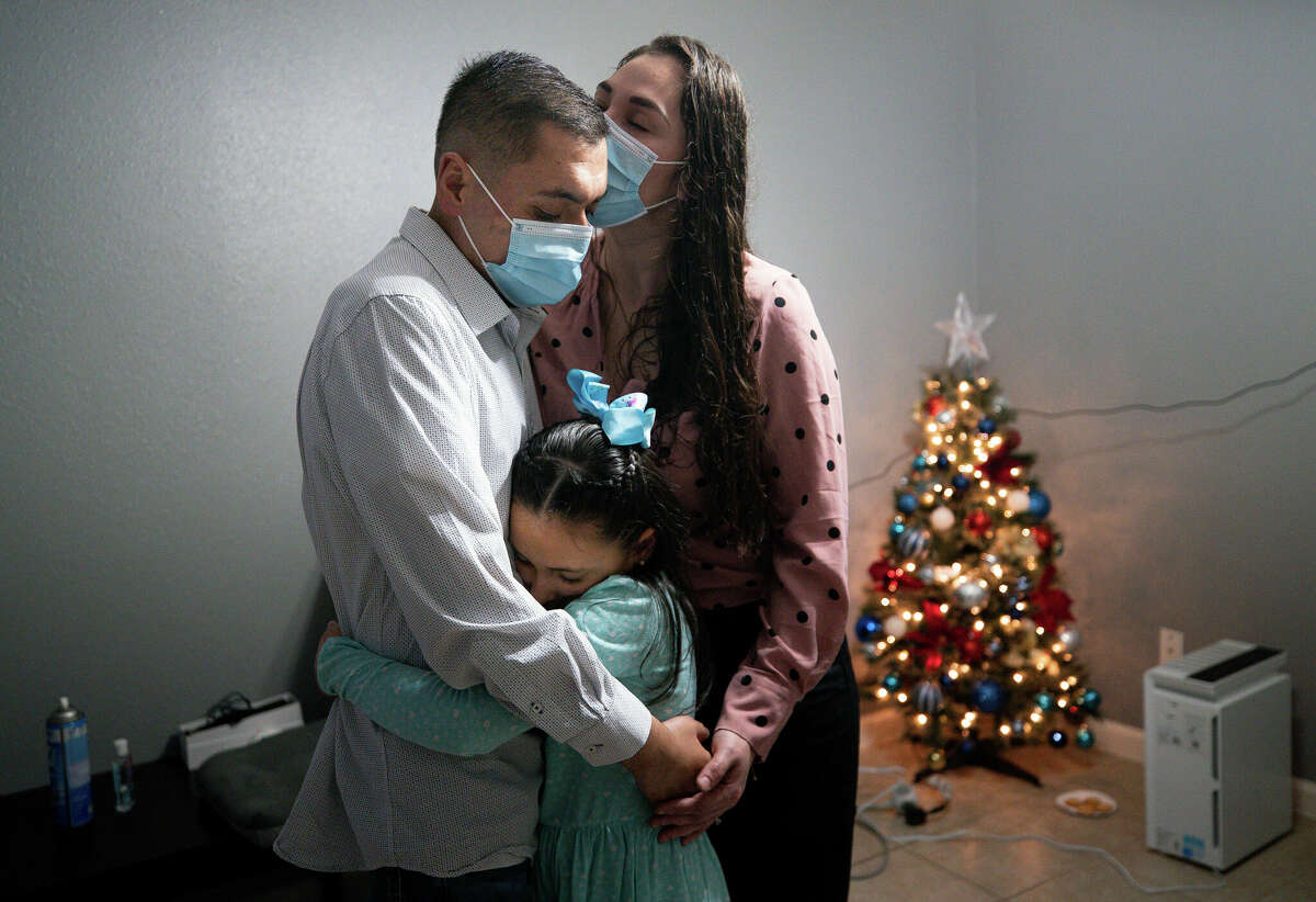 Jesús es abrazado por Perla y su hija Victoria en la sala de su casa durante la Nochebuena del viernes 24 de diciembre de 2021 en Baytown. 