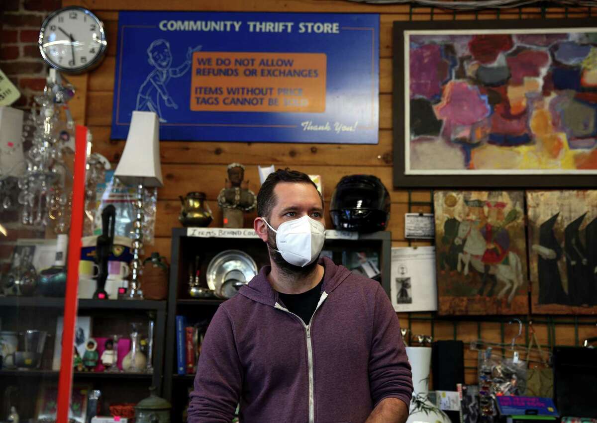 Brian Stump, executive director of Community Thrift Store, works the front counter of his San Francisco business. He was surprised to hear that the county and state are lifting mask mandates next week, and wondered if it’s premature.