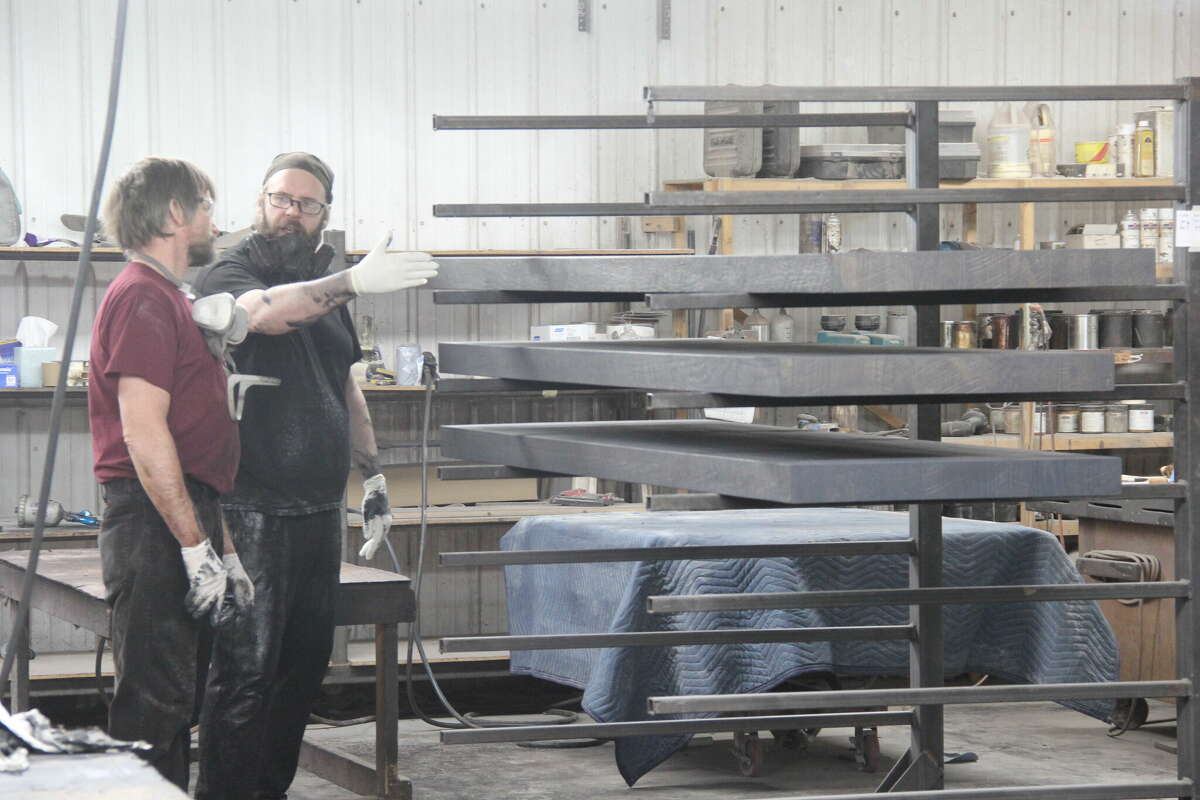 Employees at L.J. Gascho Furniture Company work on different aspects of finishing and smoothing wooden furniture for retail sale. The company plans on introducing spraying robots and autonomous carts to help speed the process and increase output.