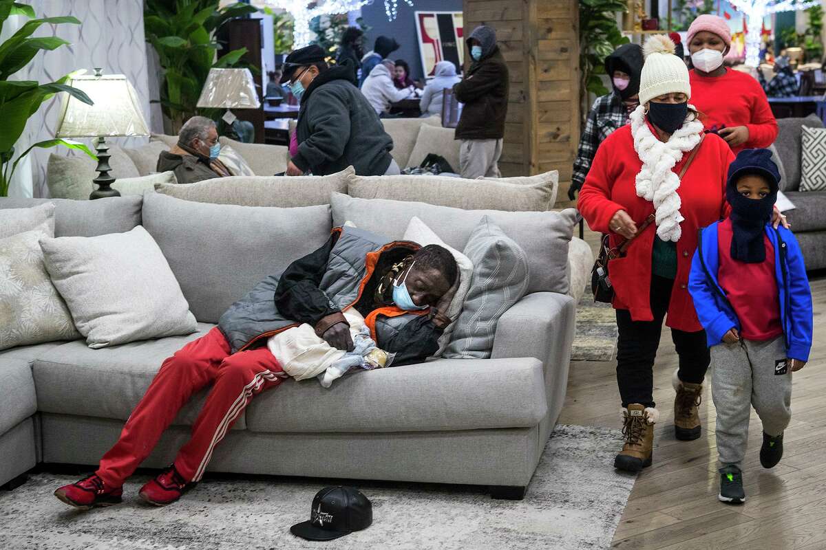 People gather at a warming shelter set up at Gallery Furniture Tuesday, Feb. 16, 2021 in Houston. As emperatures stayed below freezing Tuesday, and many in the neighborhood around the furniture store without power, Jim "Mattress Mack" McIngvale opened his store to help area residents come in from the cold.
