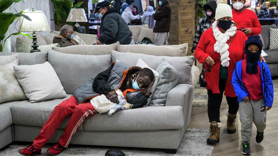 People gather at a warming shelter set up at Gallery Furniture Tuesday, Feb. 16, 2021 in Houston. As emperatures stayed below freezing Tuesday, and many in the neighborhood around the furniture store without power, Jim 'Mattress Mack' McIngvale opened his store to help area residents come in from the cold.