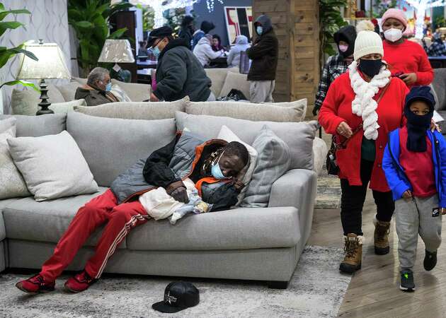 People gather at a warming shelter set up at Gallery Furniture Tuesday, Feb. 16, 2021 in Houston. As emperatures stayed below freezing Tuesday, and many in the neighborhood around the furniture store without power, Jim 'Mattress Mack' McIngvale opened his store to help area residents come in from the cold.