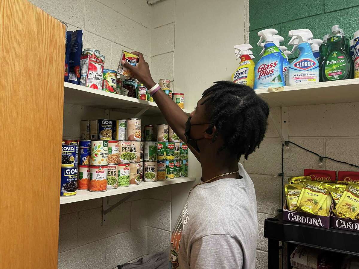 Norwalk High School senior Jeremiah Simeon stocks canned goods in the new food pantry on Feb. 10, 2022.