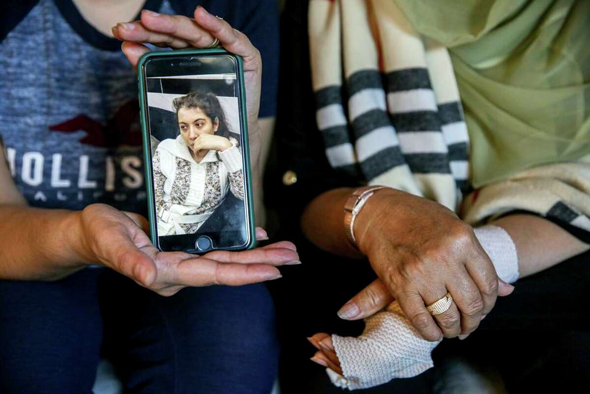 Sadaf Royeen shows a photo of her sister Arian while sitting with their mother, Gul Makai Royeen, in their San Jose home. In the chaotic U.S. withdrawal from Afghanistan in August, Gul Makai was separated from Arian, who has a developmental disability and was left behind. Five months later, the Royeen family is trying to reunite Arian with her distraught mother.