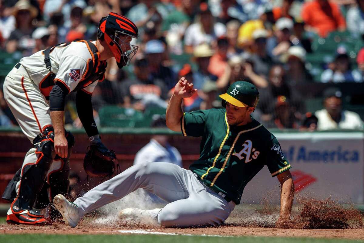 SAN FRANCISCO, CA - JULY 15: Matt Olson #28 of the Oakland Athletics slides into home plate to score a run past Buster Posey #28 of the San Francisco Giants during the fourth inning at AT&T Park on July 15, 2018 in San Francisco, California. The Oakland Athletics defeated the San Francisco Giants 6-2. (Photo by Jason O. Watson/Getty Images)