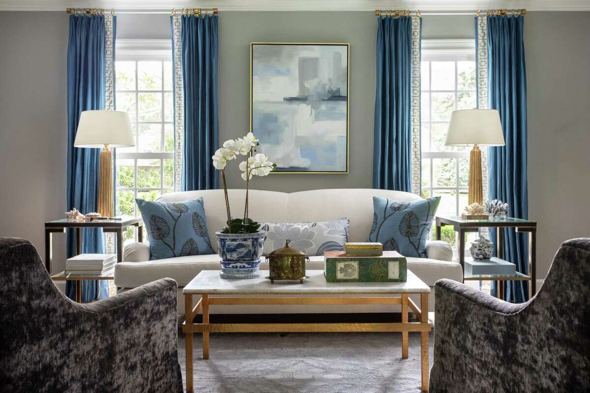 The formal living room has pops of blue in the draperies. The nearby family room/den brings in more color with chairs upholstered in bright apple green fabric.