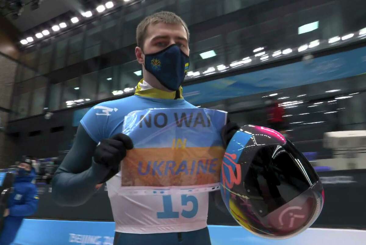 In this frame from video, Vladyslav Heraskevych of Ukraine, holds a sign that reads “No War in Ukraine” after finishing a run during the men’s skeleton competition.