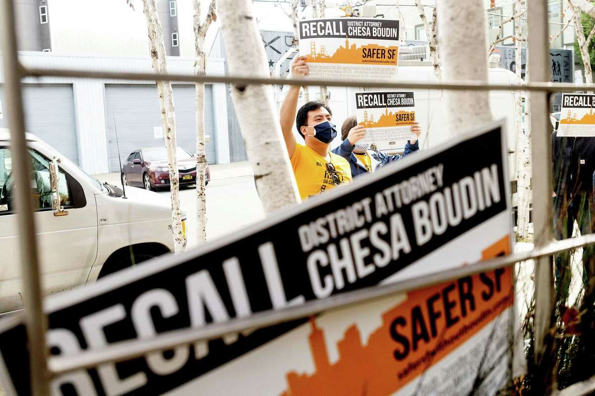 Protesters hold signs outside San Francisco District Attorney Chesa Boudin’s office on Feb. 3.
