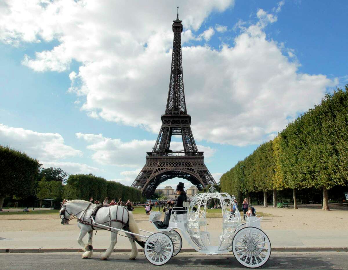 Philippe Delon (L), owner of "Paris Carriages, Horse Walking Service", next to a groom, drives a pumpkin-shaped carriage drawn by Balthazar, an 11-year-old shire horse from Sweden, the world's biggest workhorse, past the Eiffel tower on August 31, 2010 in Paris.The wrought iron made carriage, weighing 500 kilos, and decorated with little hearts, offers rides to tourists and newly weds. TOPSHOTS / AFP PHOTO / JACQUES DEMARTHON (Photo credit should read JACQUES DEMARTHON/AFP/Getty Images)