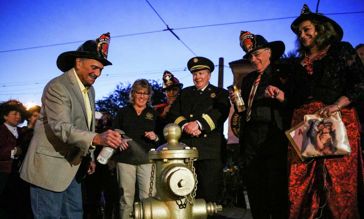Historian Ron Ross (left) sprays gold paint on a fire hydrant in 2016 to commemorate the 1906 earthquake.