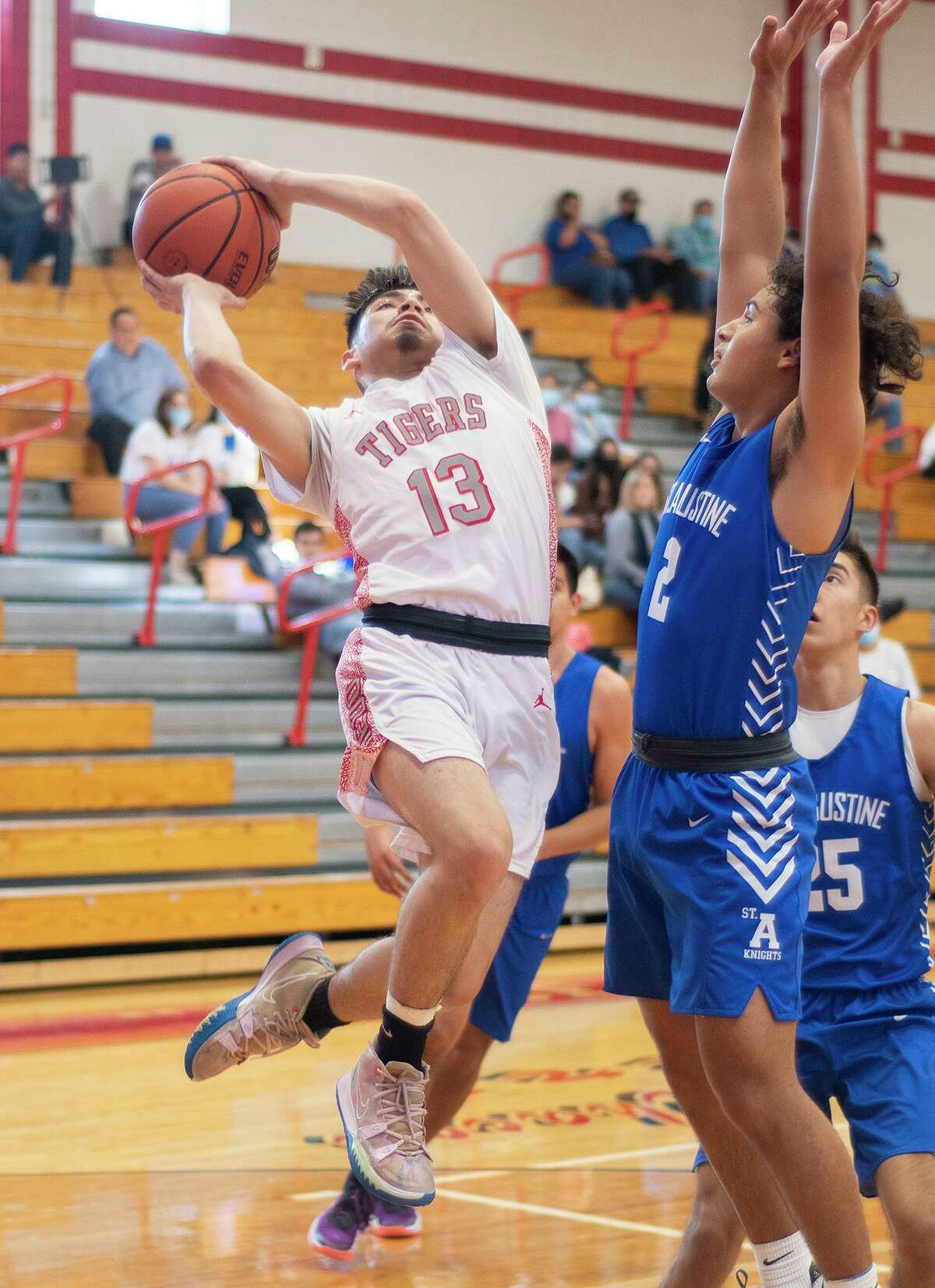 Martin High School’s Alexander Ledesma goes for a layup as St. Augustine High School’s Diego Romo defends, Tuesday, Dec. 21, 2021 at Martin High School.