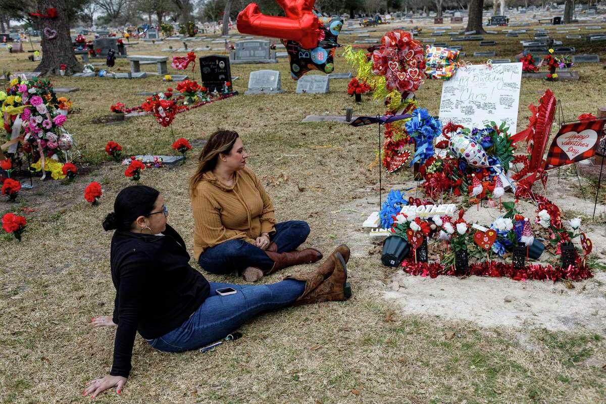 Cousins Jaclyn Garza, left, and Nicole Garza swap stories as they sit down beside their cousin Christopher Olivarez’s gravesite at Mission Park Funeral Cemetery in San Antonio, Texas, Saturday, Feb. 12, 2022. Olivarez, who died on Sept. 25, 2021, would have turned 41 on Feb. 7.