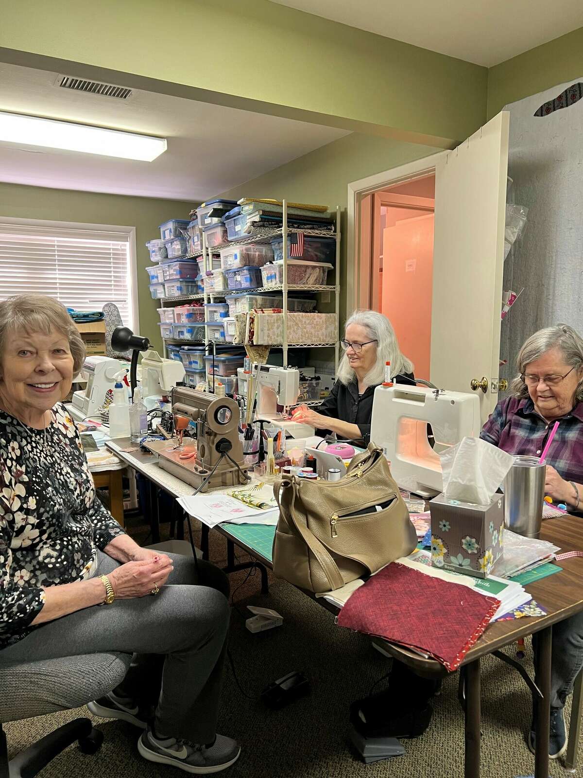 Pam Thompson, foreground, Karla Roth, background, and Kathy Hassell at work on fidget quilts in “the sweatshop” Saturday.